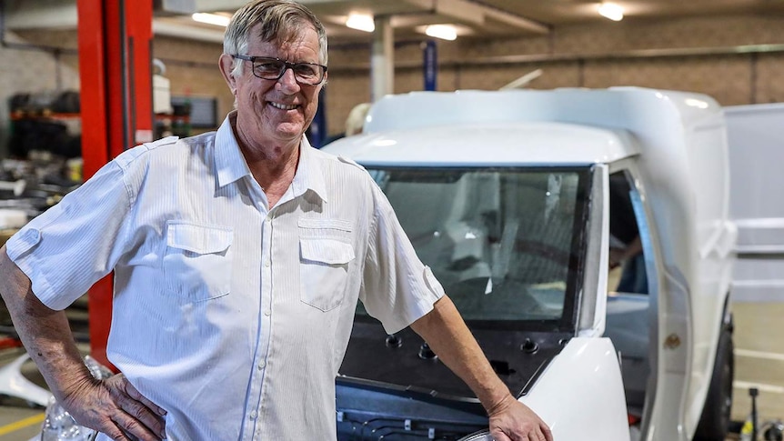 Greg McGarvie stands in front of the two-seater electric van in a warehouse at Logan.