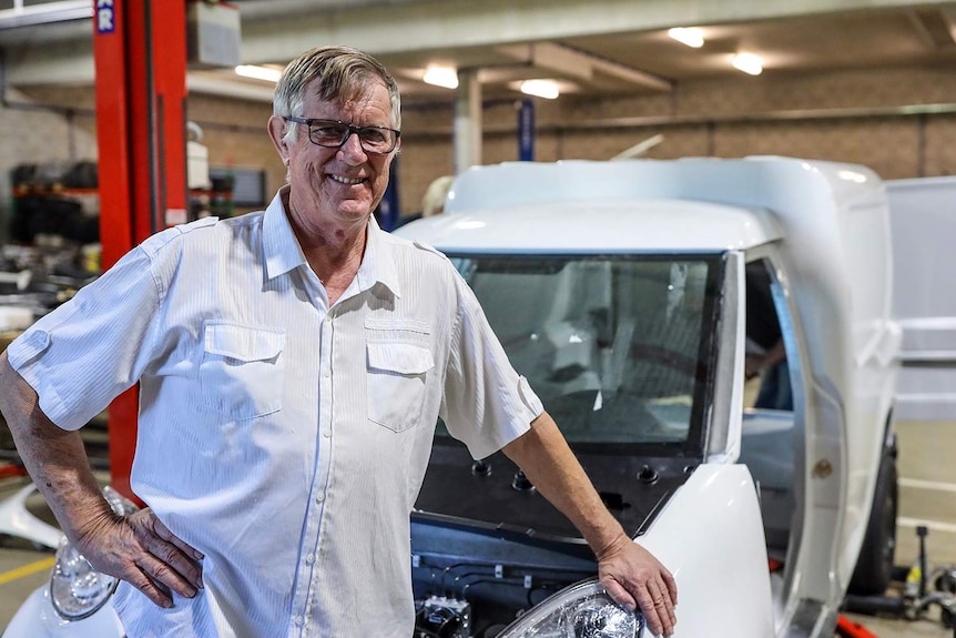 Greg McGarvie stands in front of the two-seater electric van in a warehouse at Logan.