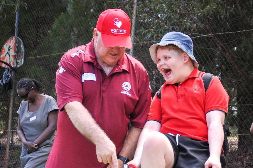 Tex Noakes plays soccer with a man helping him. 