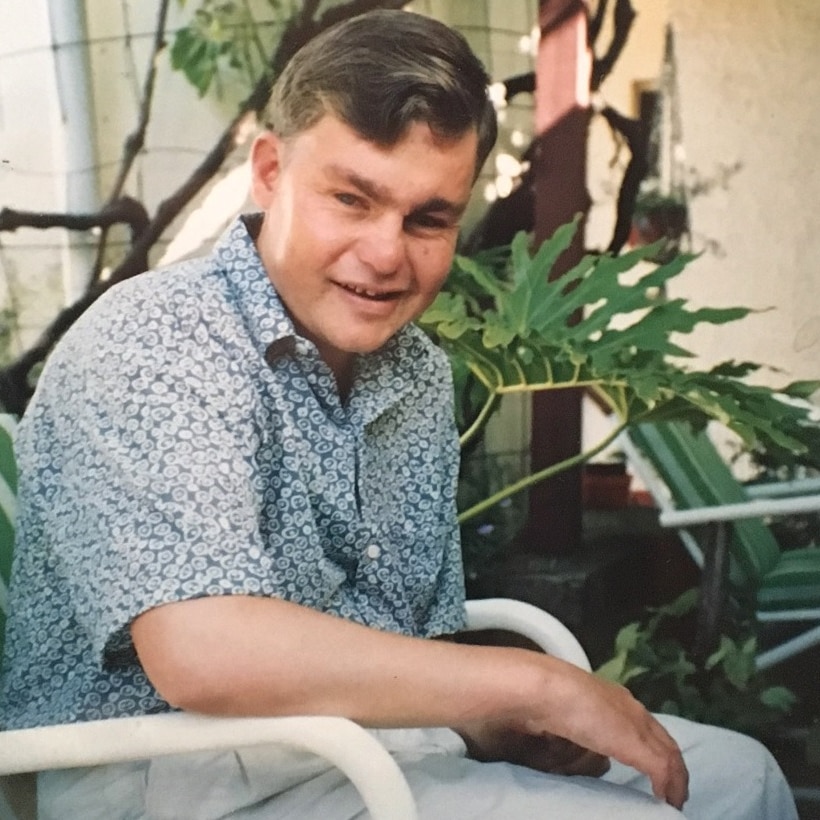 A man sits in a chair as he looks toward the camera.