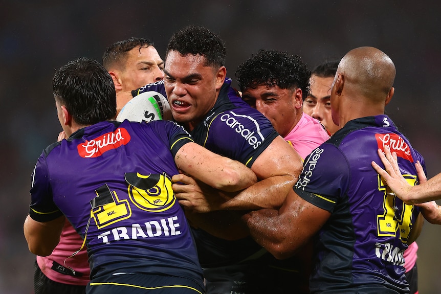 Melbourne Storm's Xavier Coates is tackled by Penrith Panthers players.
