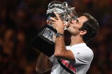 Roger Federer kisses his trophy and displays his sponsored watch