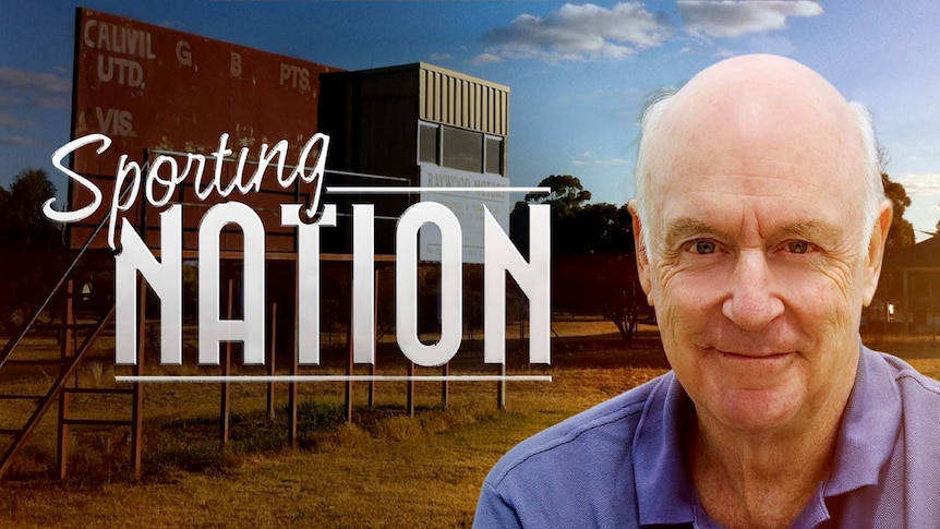 John Clarke in front of an old sign