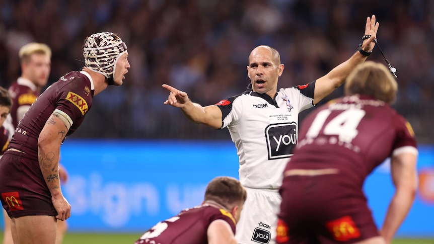 Ashley Klein points at a player off camera while holding up his other hand in the air