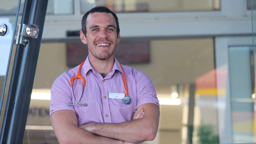 He stands outside the hospital with a stethoscope around his neck
