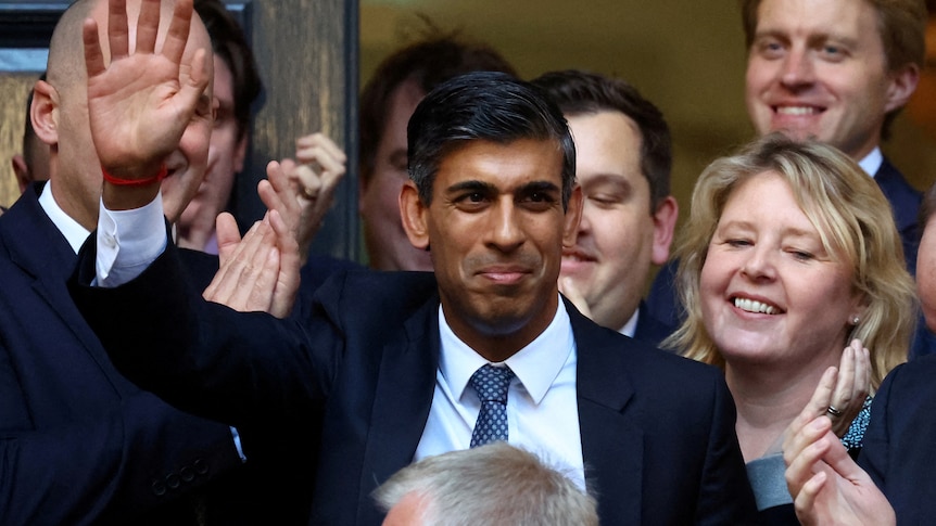 Rishi Sunak waving from the middle of an applauding crowd 