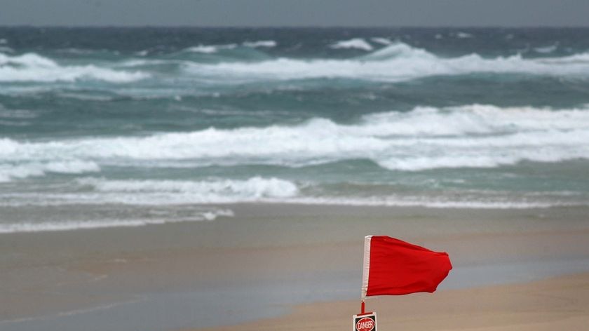 A red flag, signifying a closed beach, flies in strong winds