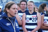 A woman in a blue jacket talks to her players