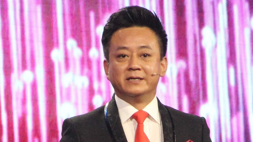 Chinese television personality Zhu Jun. He is wearing a suit with a microphone on his cheek.