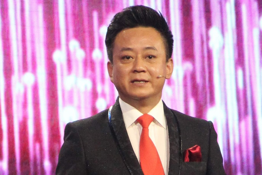 Chinese television personality Zhu Jun. He is wearing a suit with a microphone on his cheek.