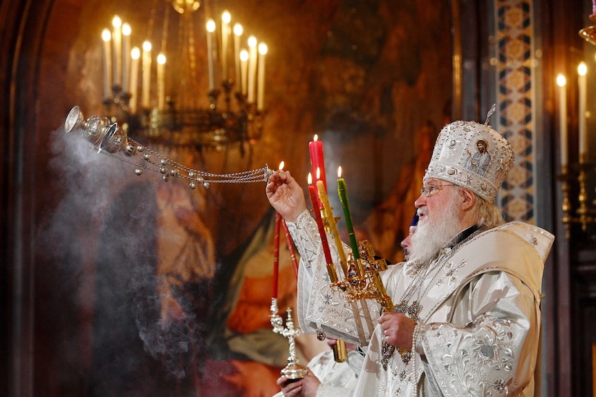 A Russian Orthodox Church patriarch swings an incense thurible.