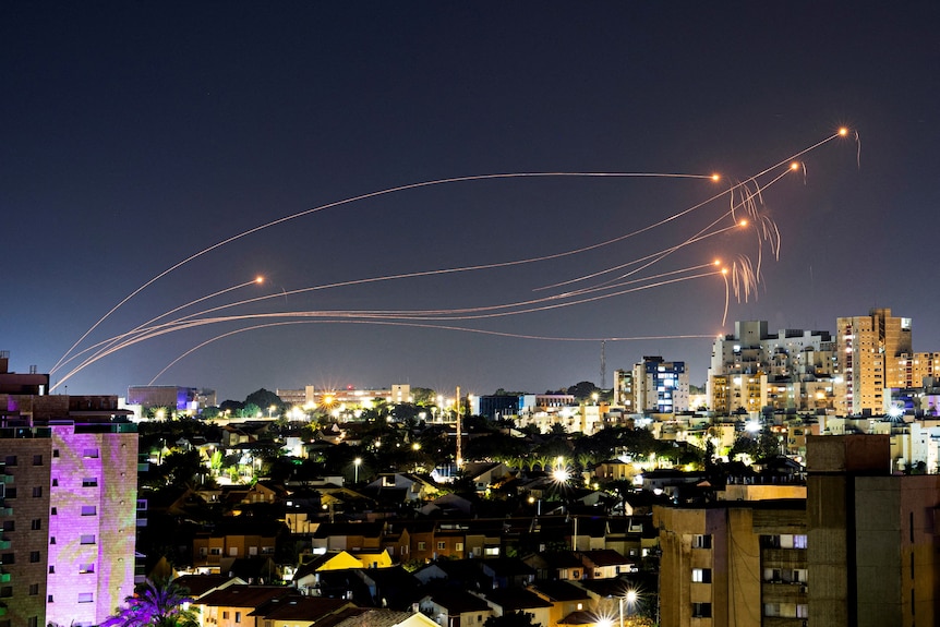 light streaks from rocket interception above a lit up horizon in israel
