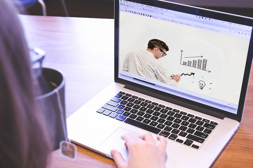 A laptop on a desk, with a cup of tea and part of a person's head on the left.