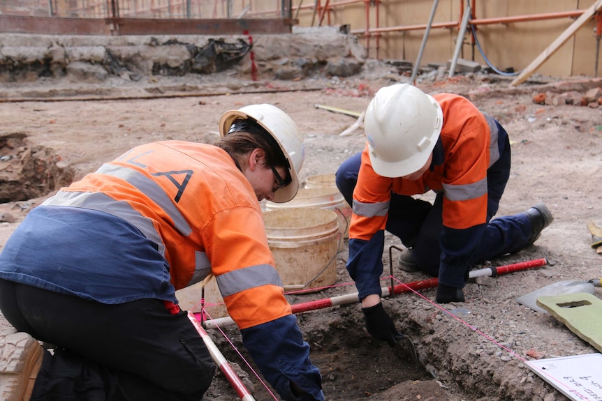 Two workers at an archaeological dig site on the corner of La Trobe St and Swanston St.