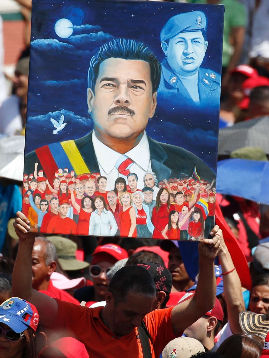 A man holds a poster of President Nicolas Maduro and Hugo Chavez