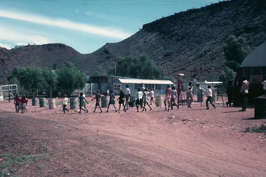 An old photo of children walking along a red dirt road