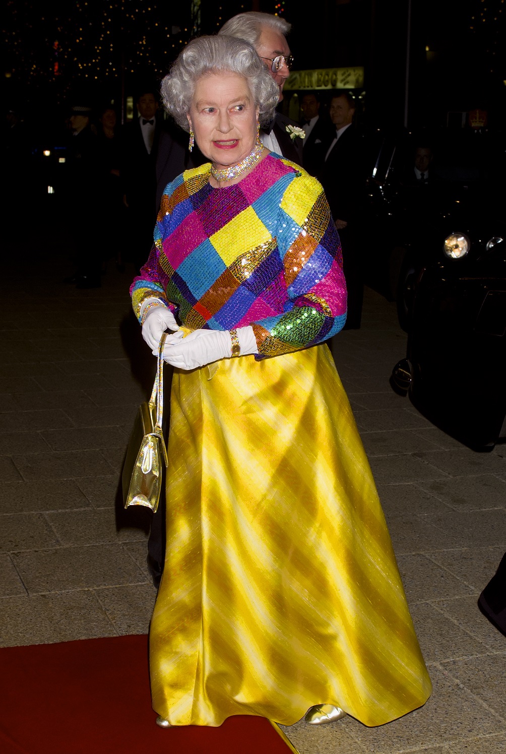 Queen Elizabeth wears a dress with a multi-coloured sequinned bodice and gold skirt