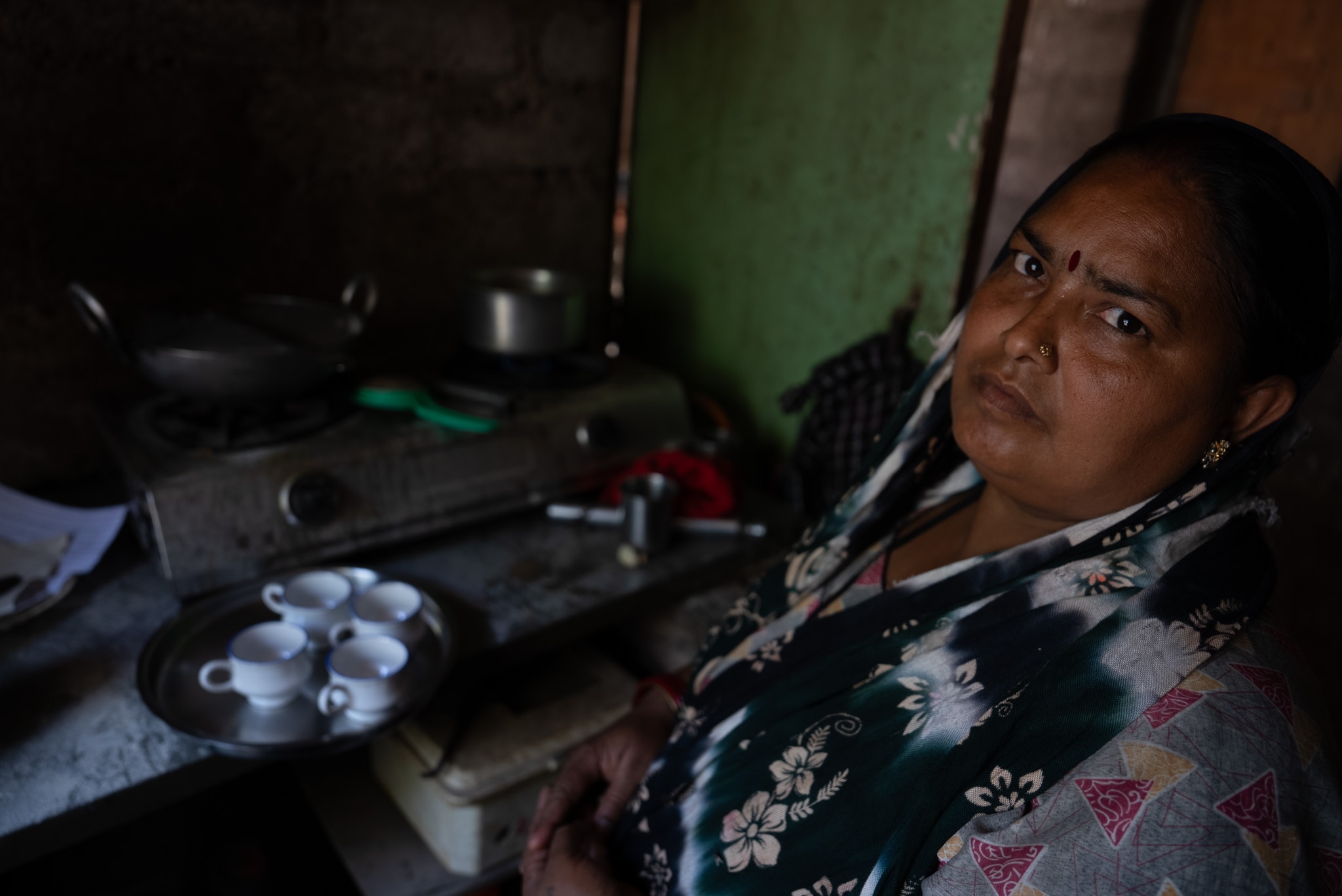 A woman looks at the camera while working in the kitchen.