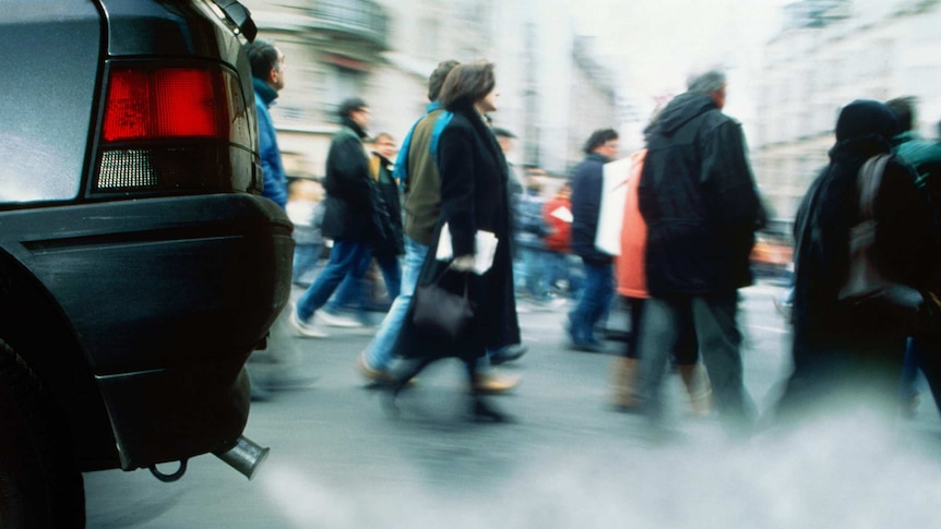 People walking past car exhaust.