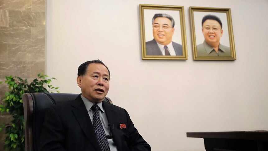 North Korean vice foreign minister seated, with the photos of Kim Jong-il and Kim Jong-un on the wall behind him.