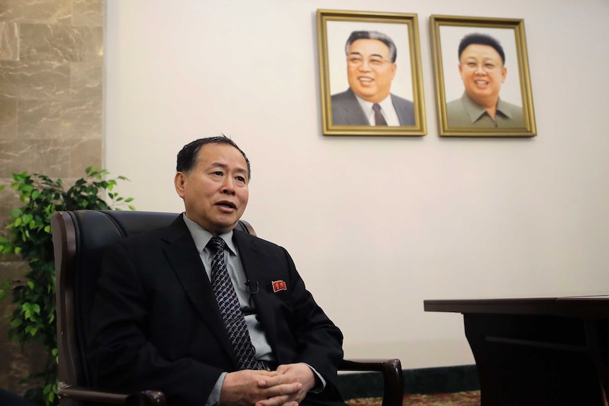 North Korean vice foreign minister seated, with the photos of Kim Jong-il and Kim Jong-un on the wall behind him.