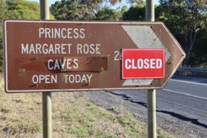 A road sign reading "Princess Margaret Rose Caves Open Today" with a closed sign posted on top