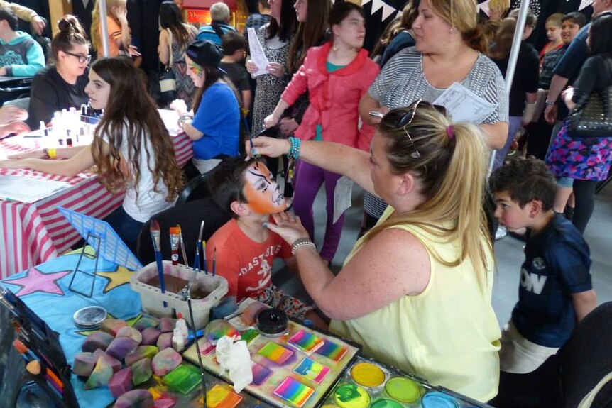 A busy scene including children having their faces painted