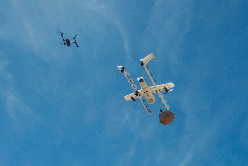 A drone delivers a package with another drone nearby