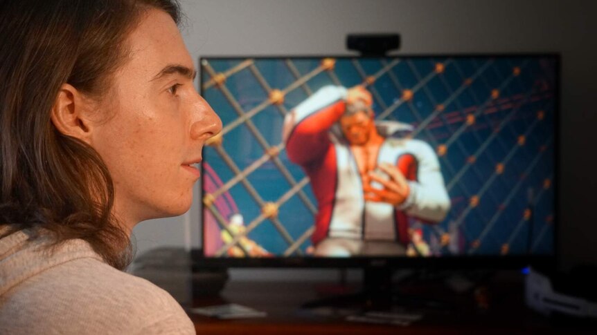 Ian Campbell sits in front of a computer screen playing Street Fighter V.