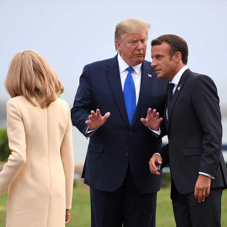 Donald Trump talks to Emmanuel Macron as Brigitte and Melania hold hands