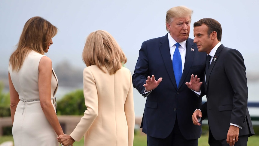 Donald Trump talks to Emmanuel Macron as Brigitte and Melania hold hands