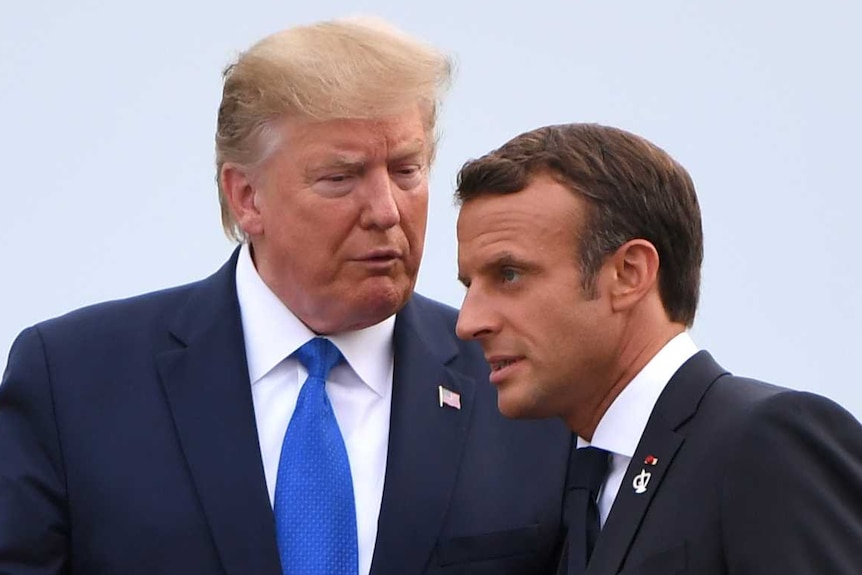 Donald Trump talks to Emmanuel Macron as Brigitte and Melania hold hands