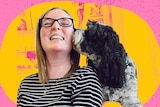 A young woman wearing glasses and a stripey top is being kissed on the cheek by her cute black dog.