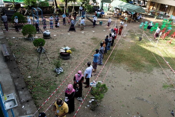 People wearing face masks line up to cast their ballots for the general election at a polling station.
