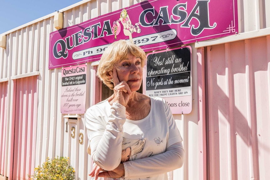 A businesswoman standing on a street corner with her property in the background.