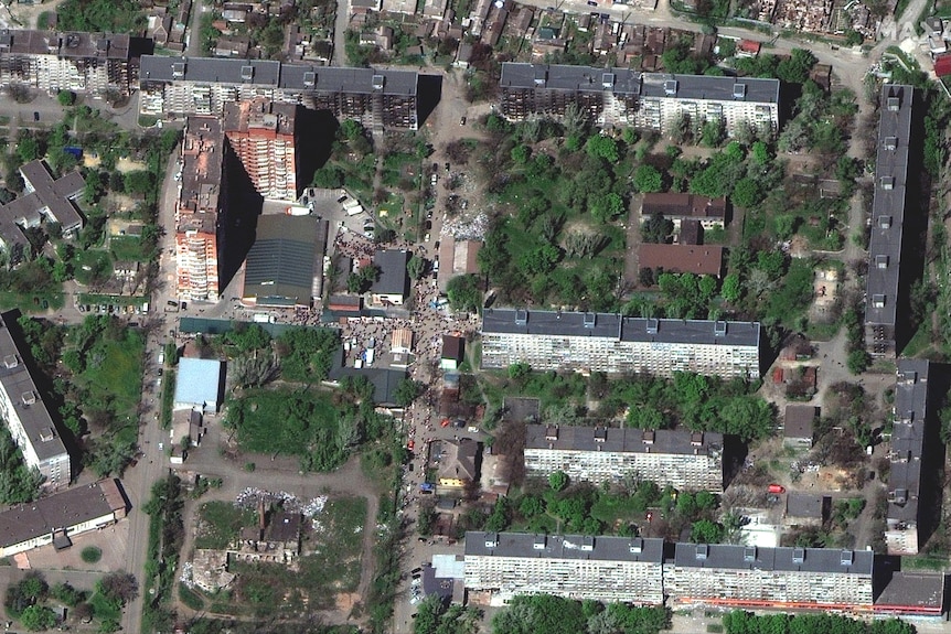 A satellite image of people gathered between buildings