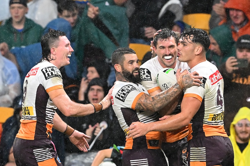 Corey Oates sonríe y es abrazado por otros tres jugadores con camisetas blancas.