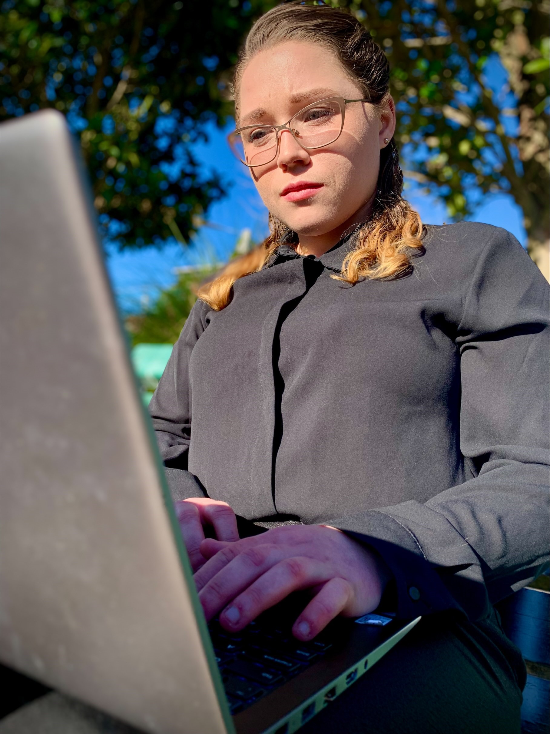 Melyssa Troy on her laptop at the park looking at a report her organisation did on consumer complaints.