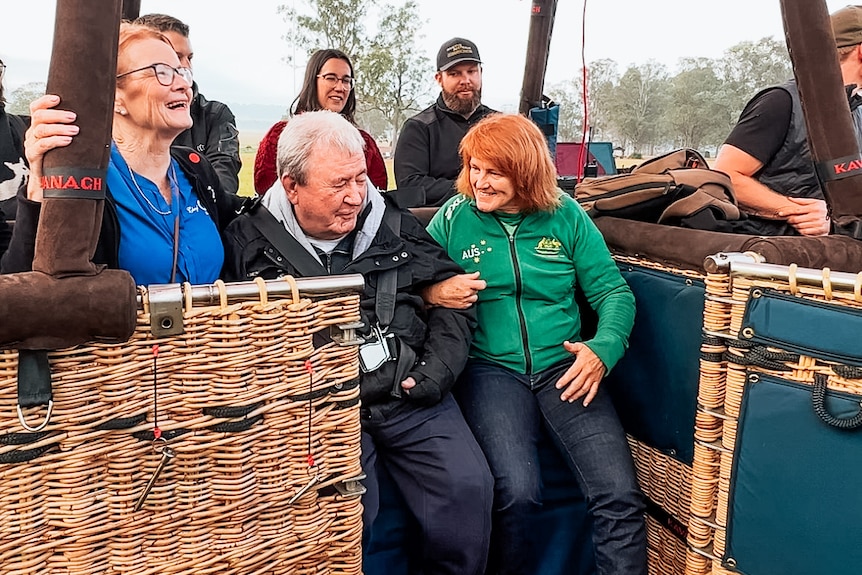 a man and a woman sitting in a hot air balloon basket that has landed