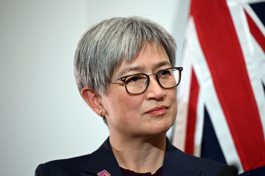 A close up of Penny Wong in glasses observing during a press conference. 