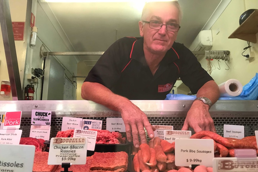 Des Barritt leans into a counter filled with sausages and mince