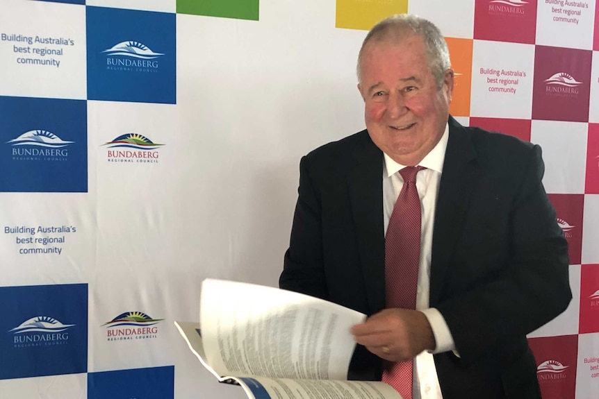 Bundaberg Councillor Steve Cooper smiles for the camera as he flips through pages of the 2020/21 budget.