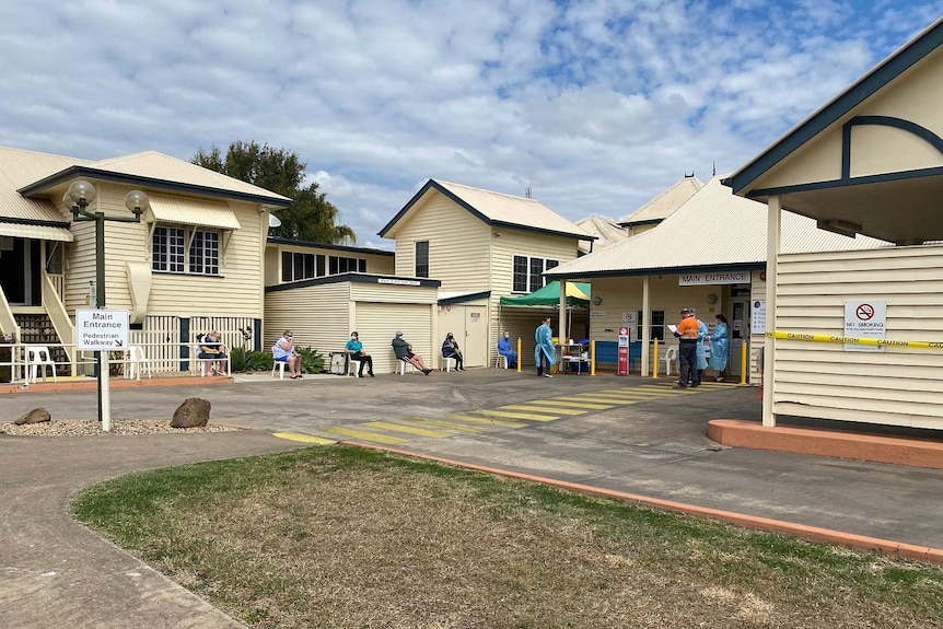 People sit on chairs, socially distancing, outside the Laidley Hospital, which is a bunch of Queenslander cottages.