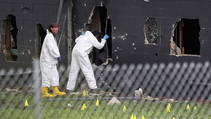 FBI agents standing outside the Pulse nightclub look into a large hole in the rear wall of the club.