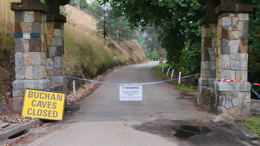 Police tape across a path. There's two signs explaining the Buchan Caves are closed.