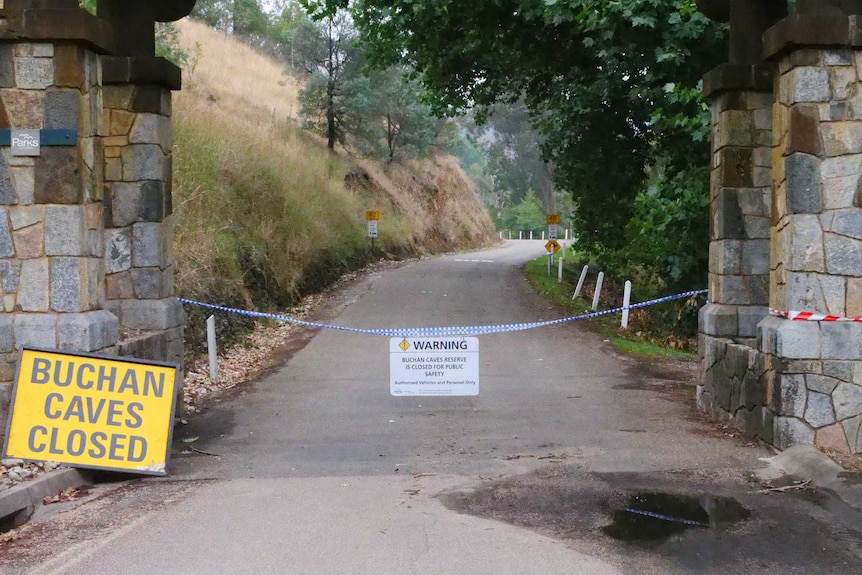 Police tape across a path. There's two signs explaining the Buchan Caves are closed.