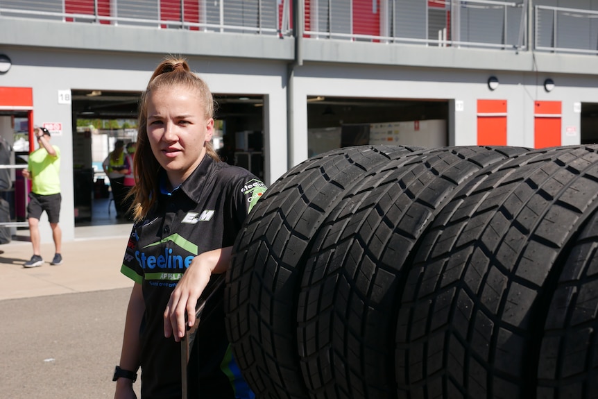 Woman leaning on rack of tyres.