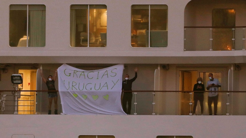 Passengers abroad a ship hold a sign reading "Gracias Uruguay".