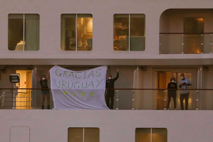 Passengers abroad a ship hold a sign reading "Gracias Uruguay".