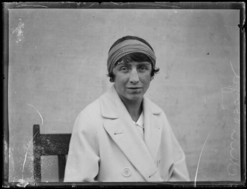 An old black and white photo of a woman with short hair sitting for a photo